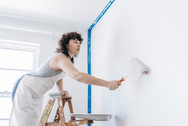 person on a ladder painting a wall